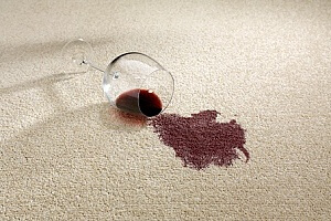 a wine glass spilled on a carpet that needs stain removal services