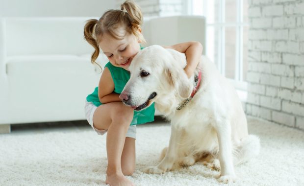 Cute girl with her dog on a clean carpet