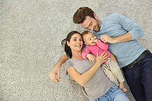 a family enjoying their time together while laying down on a carpet