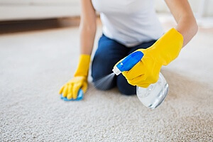 a woman cleaning her carpet that had a stain
